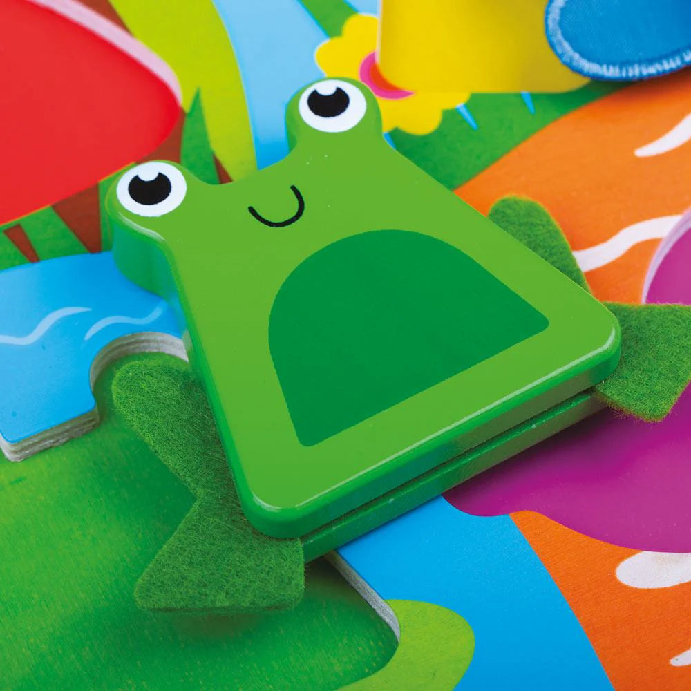 The Touch and Feel Bugs Puzzle features a vibrant, colorful puzzle piece of a smiling green frog with large eyes. Its textured background showcases bright colors and abstract shapes, encouraging children to touch and enjoy the playful theme.