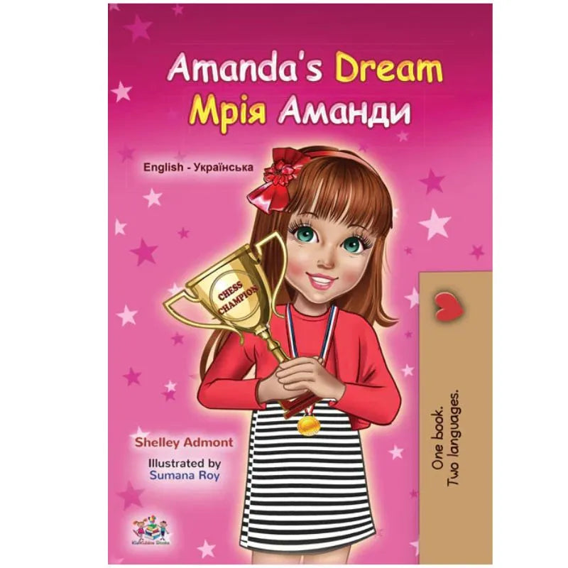 Book cover of "Dual Language Book Amanda's Dream English/Ukrainian Children's Book," showing a smiling brown-haired girl in a red shirt and striped skirt holding a trophy on a pink starry background.