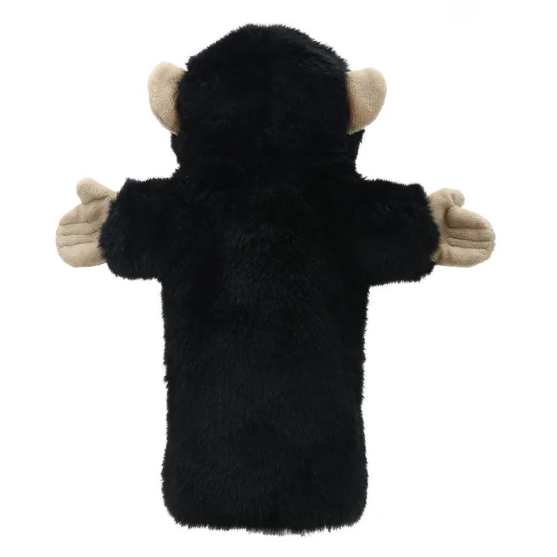 The Puppet Company Long Sleeved Puppet Chimp is a black plush hand puppet resembling a monkey with tan-colored ears and hands. It is depicted facing away, arms outstretched, inviting imaginative play against a plain white background.