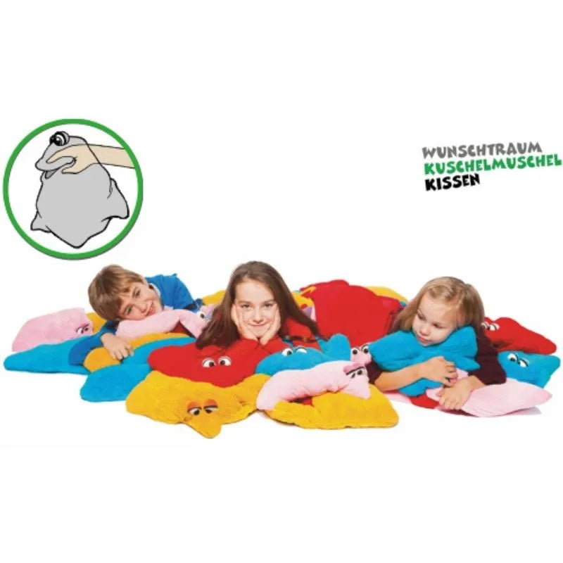 Three children lie on colorful star-shaped sensory pillows with cartoon eyes. In the corner, an illustration shows a hand holding the foldable plush toy pillow. Text reads "Dream Cuddle Pillow Yellow.