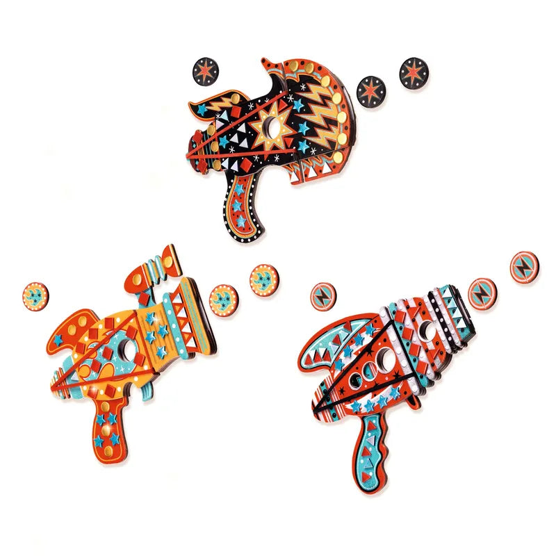 Three vibrant Djeco Mosaics & Stickers Kosmik toy ray guns made of wood, adorned with geometric patterns in shades of red, orange, yellow, blue, and black. Each gun is part of a creative kit that includes a matching disk featuring similar patterns and colors placed nearby.