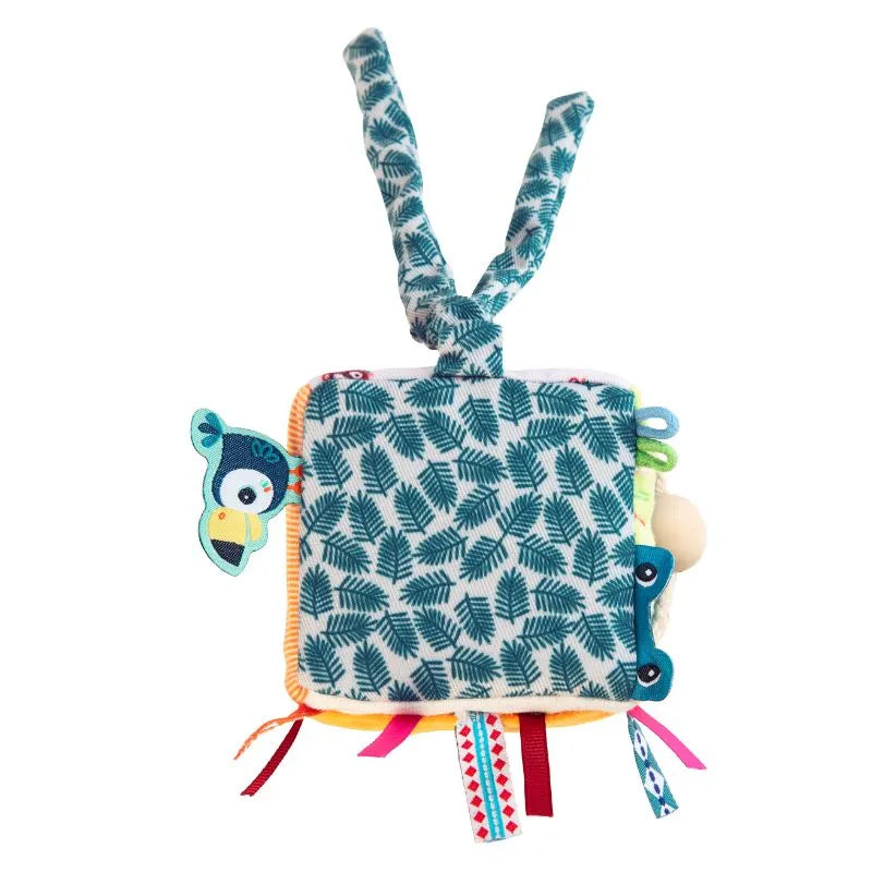 The Lilliputiens I'm Discovering Jack Activity Cube is a vibrant baby toy featuring a leaf pattern with a blue and green bird design. It has textured tags, ribbons along the edges, and two fabric loops for easy attachment. An ideal first toy and thoughtful baby gift.