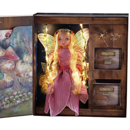 The My Forever Tooth Fairy Gift Set features a doll with long blonde hair, a pink dress, and glowing wings, presented in an open gift box decorated with magical forest art and compartments labeled “Magic Mail” and “Tooth Tale.”.