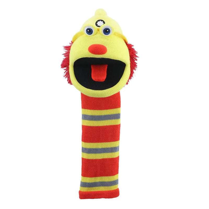 The Puppet Company Sockette Flint is a colorful, eco-friendly hand puppet with a yellow face, googly eyes, red nose, fuzzy hair, wide black mouth, and a striped red, yellow, and gray sock body—perfect for expressive play.