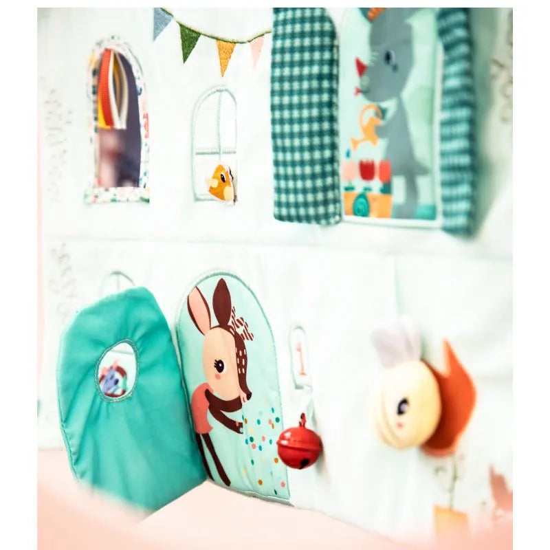 The Lilliputiens "I'm Discovering Stella & Joe House Soft Discovery Panel" is a colorful children's playhouse with illustrated animals like a deer and rabbit, vibrant bunting, and interactive elements such as a plush bell and flaps—great as a baby's first toy or gift.