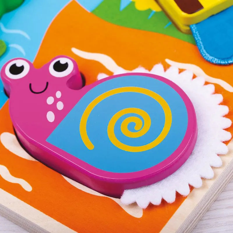 A colorful wooden snail puzzle piece from the Touch and Feel Bugs Puzzle has a pink body, blue shell with a yellow spiral, and cheerful, cartoonish facial features. It rests on a vibrant background, inviting you to explore its playful textures and touch-and-feel elements.