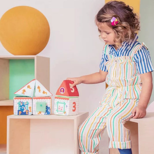 A little girl playing with Lilliputiens Farm House Stacking Cubes.